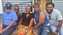 Vernice and family members sitting together and smiling on steps of house