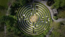 aerial shot of a labyrinth made from green hedges surrounded by trees